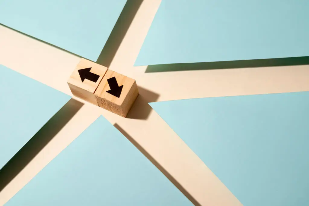 Wooden blocks with arrows indicating direction on a blue and white background, symbolizing decision-making and project management for remote teams.